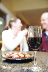 A glass of red wine with a plate of dried dates.
