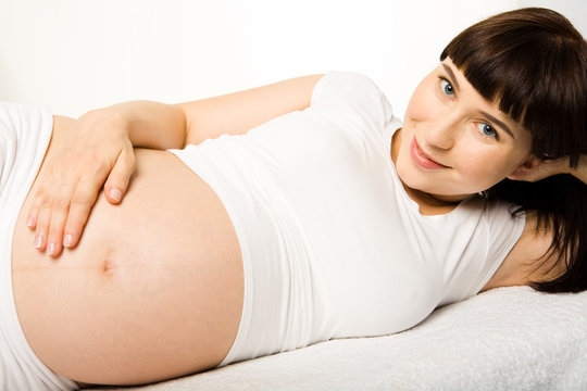 Photo of pregnant woman lying and looking at camera