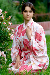 Girl in a pink yukata near rose-bush.