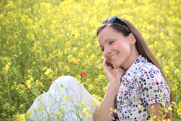 pretty young woman talking on mobile phone on a meadow