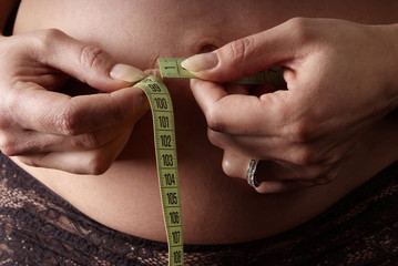 woman measure girth of belly with measuring tape