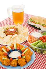 Table set with party snack food platters and a pitcher of beer.