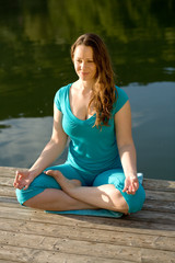 Junge Frau betreibt Yoga am Wasser