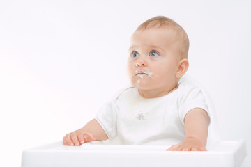 baby boy with dirty face sitting in highchair