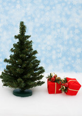 Tree with two red presents on snow with snowflake background