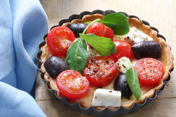 Small tart with cherry tomatoes, goat's cheese, black olives