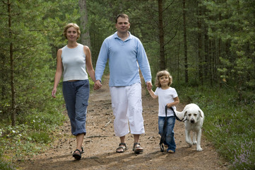 Obraz premium Happy family with dog walking in the forest