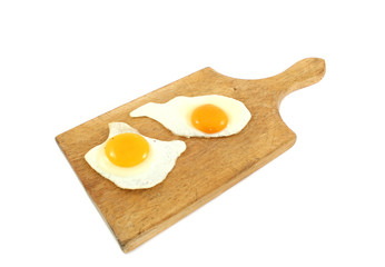 two fried eggs on wooden board