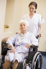 Nurse Pushing Senior Woman In Wheelchair