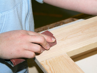 Young student trainee using sandpaper on wooden frame