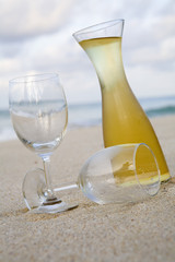 Carafe of white wine and glasses on beach