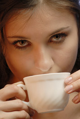 young woman with  cup in  hand looks,  close up