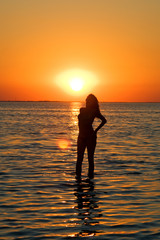 Fototapeta na wymiar Silhouette of the young woman on a gulf on a sunset