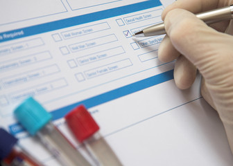 Doctor ticking box on a blood test form - obrazy, fototapety, plakaty