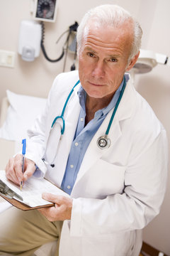 Middle Aged Doctor Writing On His Clipboard