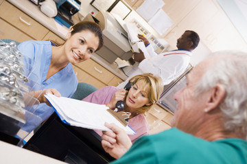 Nurses Being Handed A Clipboard At The Reception Area In A Hospi