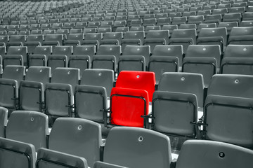 black and white picture of stadium seat with only one red