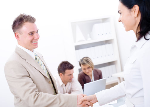 Businessman and businesswoman shaking hands in office,