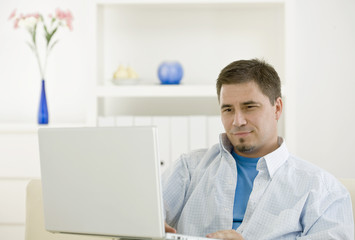 Fototapeta premium casual man teleworking using laptop computer at home.