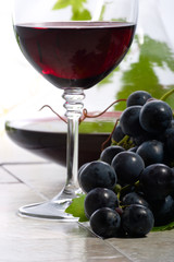 Glass of red wine, decanter and fresh cut black wine grape