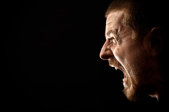 Face of angry man screaming isolated on black