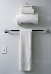 Three white terry cloth towels on towel rack and towel holder
