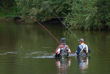 Two fishermen stand in the river and fish