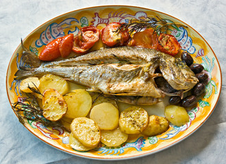 Fresh fish cooked in owen with potatoes, tomatoes and olives.