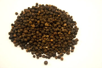 Whole black peppercorns on white background
