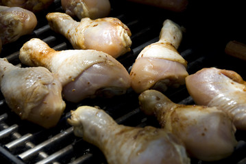 Raw chicken legs being grilled