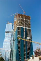 Fototapeta na wymiar Sky-scrapers construction. Cranes and buildings over blue sky...