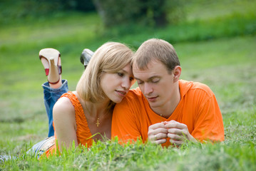 Loving couple lies and embraces on a green grass