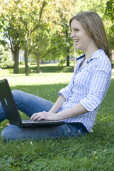 Female using the computer with legs stretched out in the grass