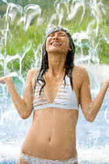 Obraz premium A pretty woman standing under a waterfall in a pool