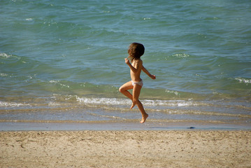 NIÑA SALTANDO EN LA PLAYA