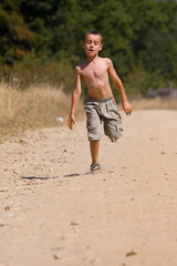 Seven year old kid running on a dusty road in the countryside