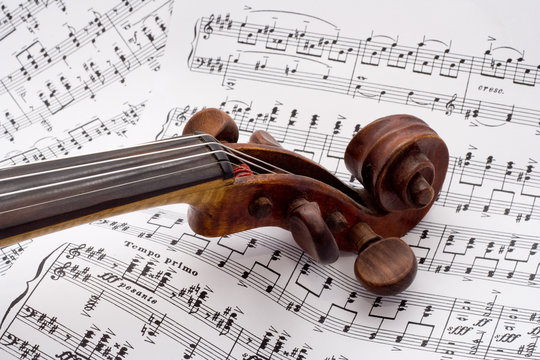Old violin scroll on a sheet music