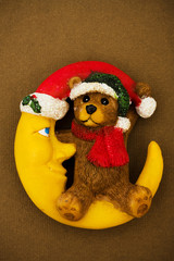 Teddy bear sitting on moon wearing Santa hat