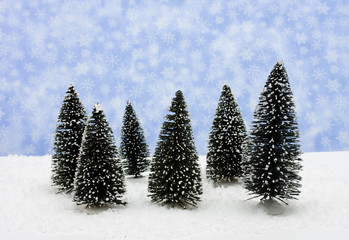 A group of evergreen trees on snow with snowflake background