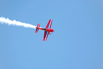 aerial acrobatics - red propeller plane with smoke blue sky © Sascha Burkard