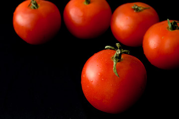 Tomatoes on a black background with drops of water.