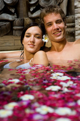 A young couple together in a bath with petals and flowers