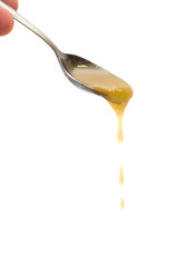 Honey drip from spoon on white background