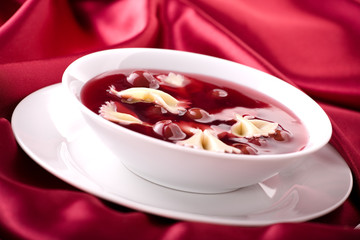 Cherry soup with pasta on the red satin
