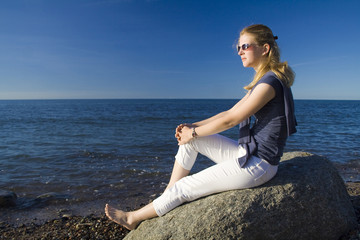 Fototapeta na wymiar Frau sitzt am Strand