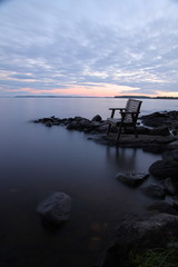 Fototapeta na wymiar Sunset by the lake with empty chair, long exposure