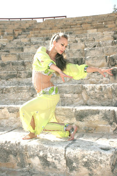 Beautiful belly dancer in green on the ancient stairs.