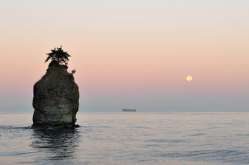 siwash rock at sunrise and moonset, stanley park, vancouver