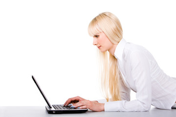 Fototapeta premium Image of pretty female lying before laptop and typing