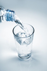 Glass of water being filled from a plastic bottle